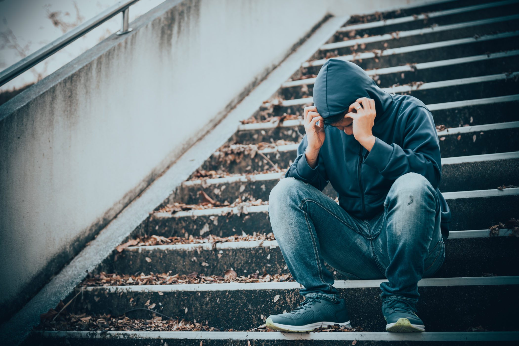 Man sitting on stairs outside thats struggling